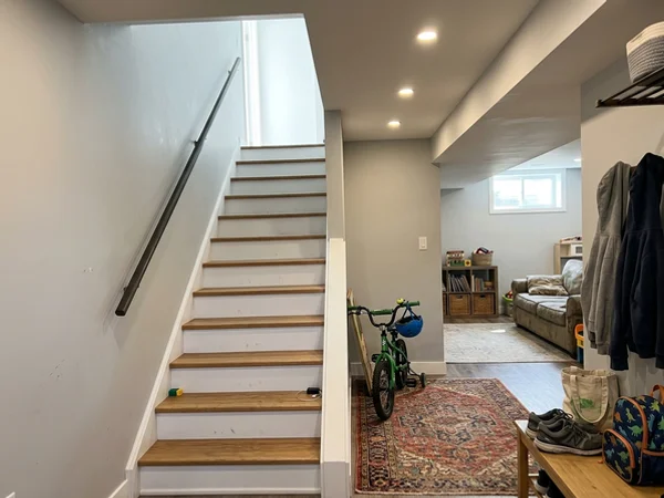 Same basement stairs after renovation with closed risers and handrail