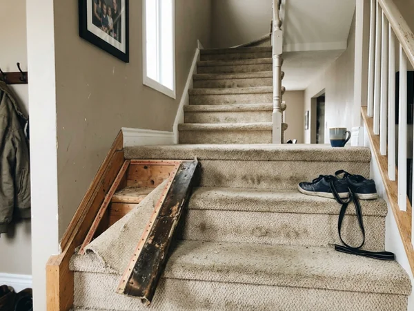 Worn carpeted staircase before vinyl capping