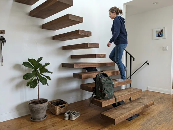 Finished floating-look walnut staircase against a white wall