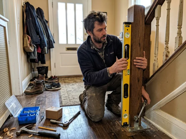 Installer checking a new newel post for plumb