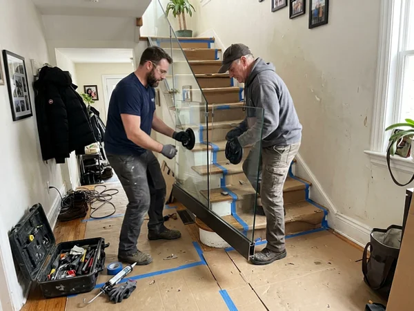 Two installers setting a glass panel into the base shoe