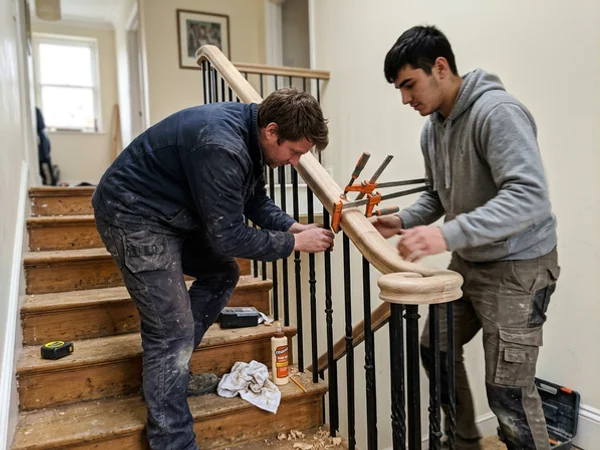 Crew fitting a laminated curved handrail section on site