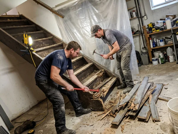 Crew removing rotted basement treads behind a dust barrier