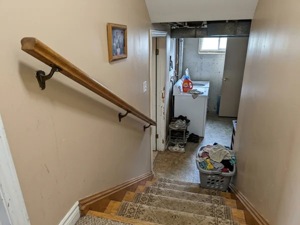 Wall-mounted oak handrail on a closed basement staircase